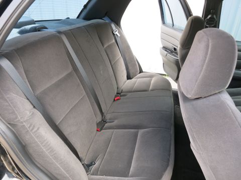 2001 Ford Crown Victoria - The interior of a car shows the rear bench seat and passenger doors ajar.