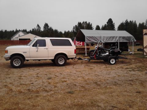 1990 Ford Bronco - White 1990 Ford Bronco is seen towing a motorcycle on a trailer in a rural setting.