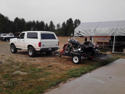 1990 Ford Bronco - White 1990 Ford Bronco is seen towing a motorcycle on a trailer under an overcast sky.