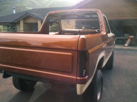 1982 Ford Bronco - This 1980s Ford Bronco shows significant damage to its roofline and appears to be undergoing repairs.