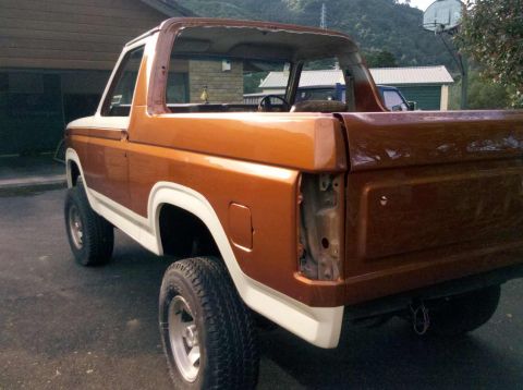 1982 Ford Bronco - This 1982 Ford Bronco is shown from the rear 3/4 angle, a two-tone orange and white paint scheme and a removable top.