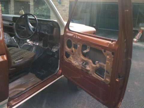 1982 Ford Bronco - The interior of a 1980s Ford Bronco shows the door panel removed, revealing the vehicle's internal structure and insulation.