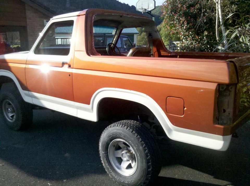 Orange and white Ford Bronco with missing taillight, seen from the rear quarter