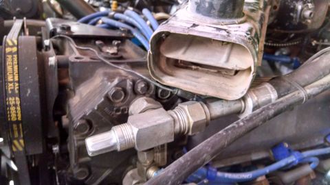 1979 Ford F-150 - Close-up of engine components including an air intake duct and compressor, with visible hoses and a belt.