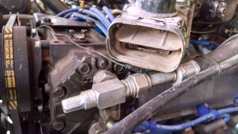 Engine air intake duct and compressor with blue hoses and a black belt labeled PREMIUM XL