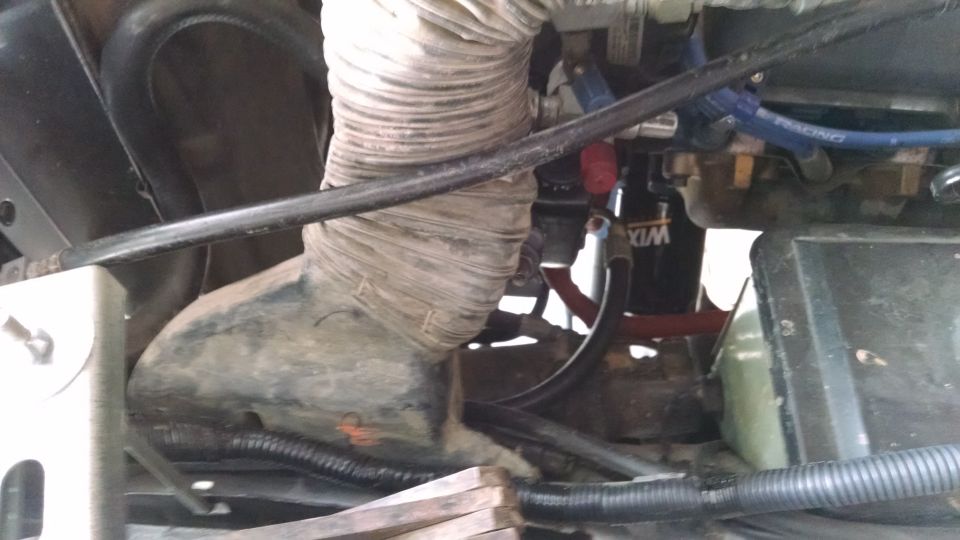 Engine bay with large corrugated hose, WIX oil filter, and blue "RACING" hose