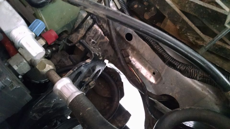 Close-up of engine bay hoses and metal brackets, with some wiring