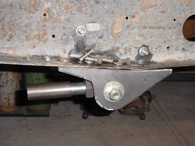 Fabricated steel mounting bracket bolted under a Bronco frame rail, with threaded spacer and loose hardware nearby