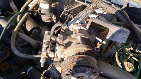 1979 Ford F-150 - Close-up view of an engine compartment, focusing on the AC compressor and associated plumbing.