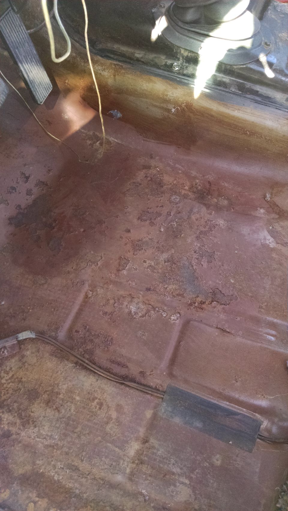 rusted floor pan with pedals visible