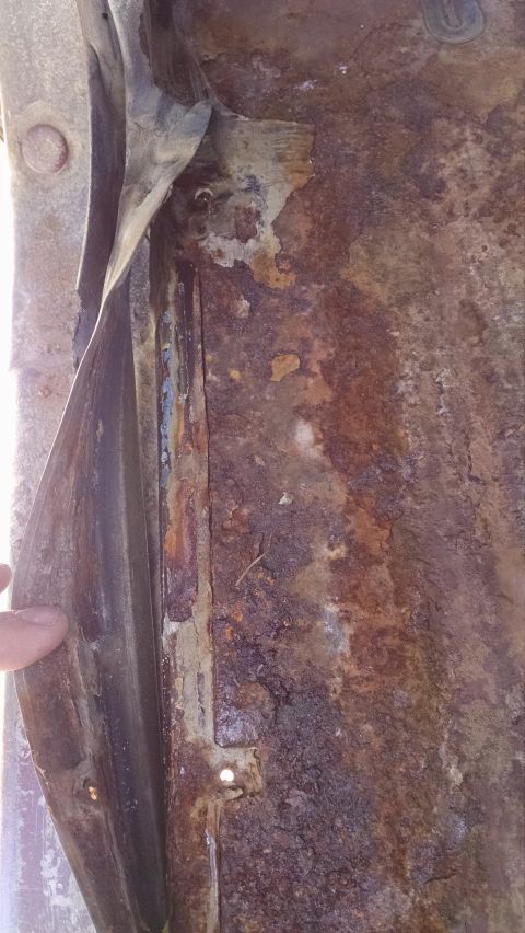 1979 Ford F-150 - Close-up view of a heavily rusted floor panel, showing significant deterioration and peeling paint.