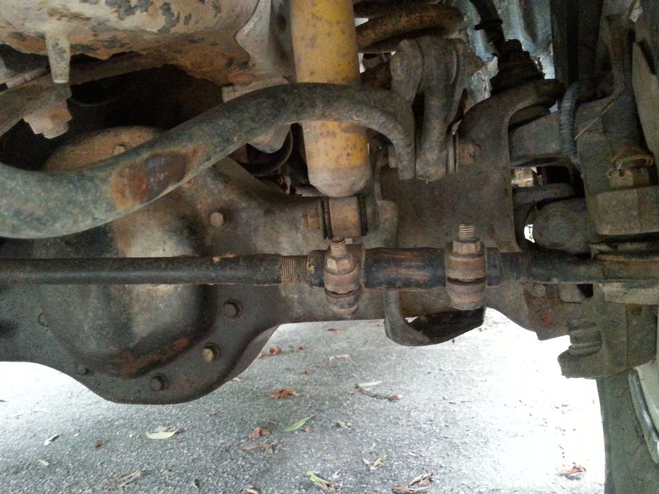 Underside view of front solid axle, tie rod ends, sway bar, and yellow shock on a 1994 Ford Bronco