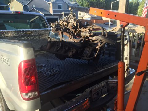 1978 Ford Bronco - An engine is being removed from a pickup truck using an engine hoist, with a toolbox visible in the truck bed.
