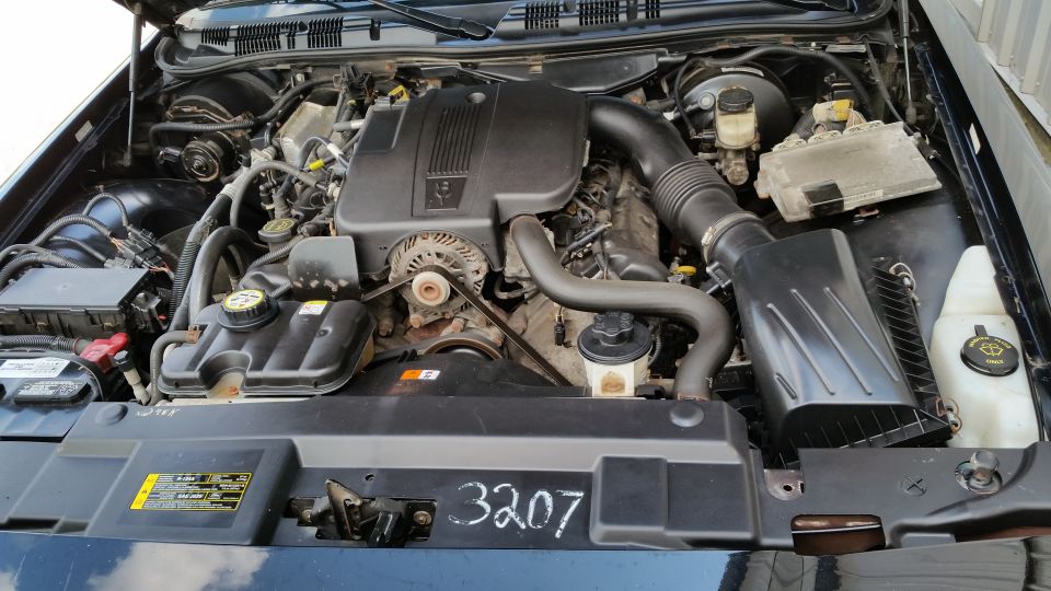 2001 Ford Crown Victoria engine bay with V8 engine, air intake, and battery visible. Number 3207 is written on the black cover