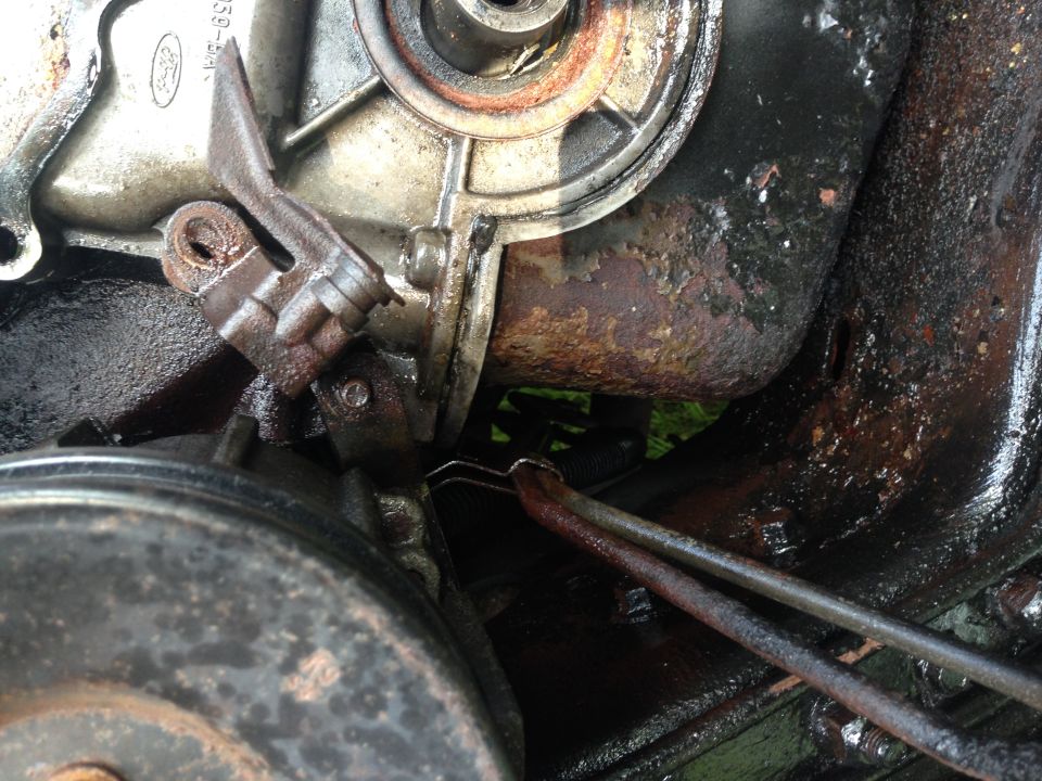 Engine timing cover with metal bracket and hoses. Ford logo visible