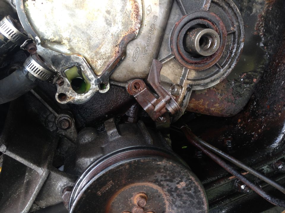 Ford engine timing cover with green fluid leak, pulley visible below