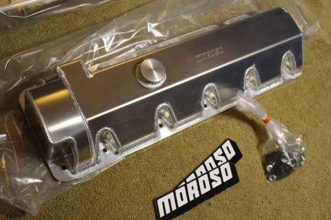 2003 Ford Crown Victoria - plastic-wrapped fabricated aluminum valve cover with a filler cap and hardware bag, displayed above a black Moroso badge.