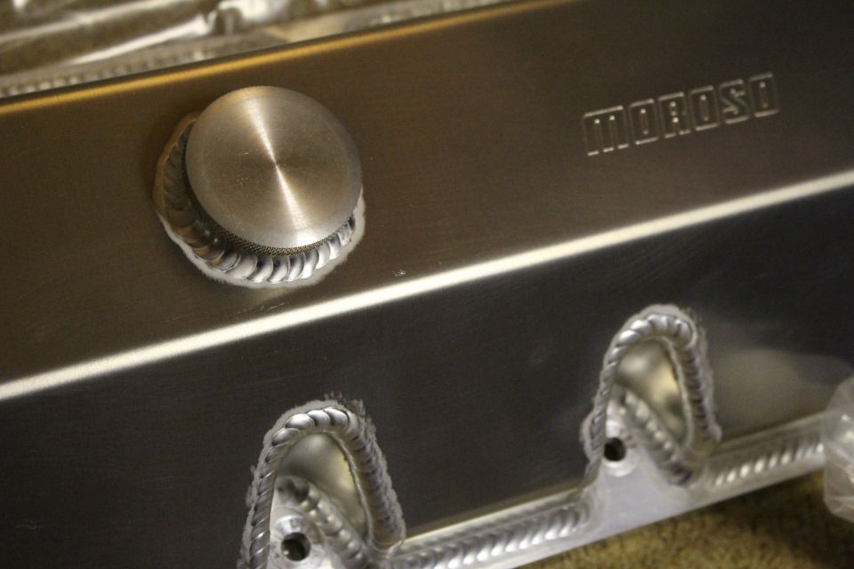 Close-up of a brushed aluminum valve cover filler cap and Moroso stamp with welded bosses