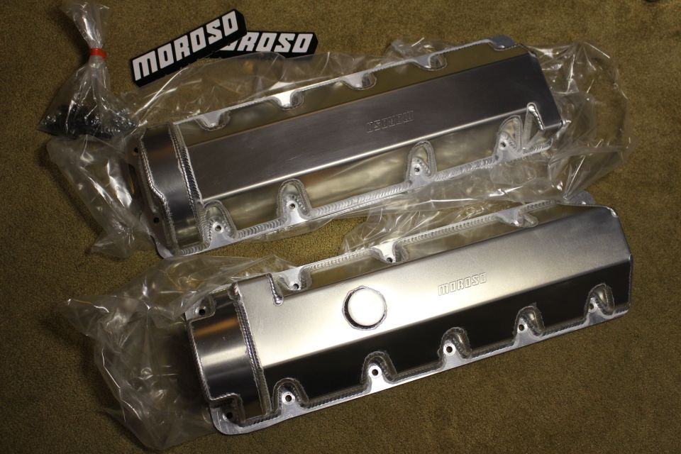 Pair of fabricated aluminum valve covers with filler cap and black Moroso badges on carpet