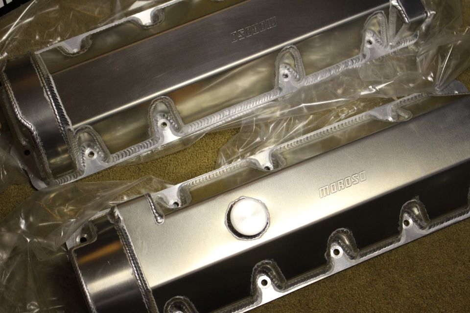 Two fabricated aluminum valve covers with welded bosses and Moroso stamps on carpet