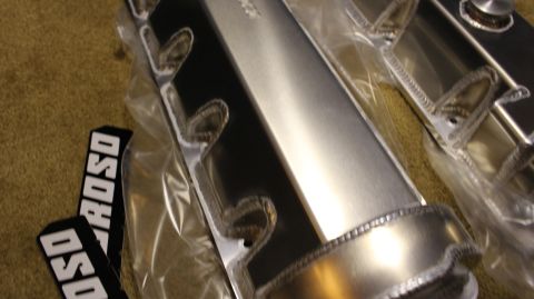 2003 Ford Crown Victoria - Close-up of brushed fabricated aluminum valve covers in plastic wrap, with MOROSO badges resting alongside.