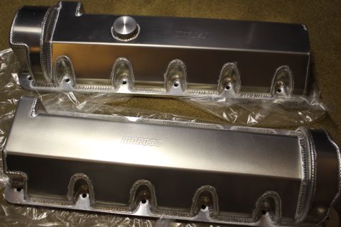 2003 Ford Crown Victoria - pair of fabricated aluminum valve covers with rope-welded bolt bosses and Moroso stamps, displayed on carpet.