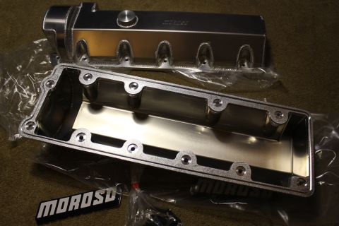 2003 Ford Crown Victoria - fabricated aluminum valve cover next to one turned to show its machined underside with bolt holes, near MOROSO badges.