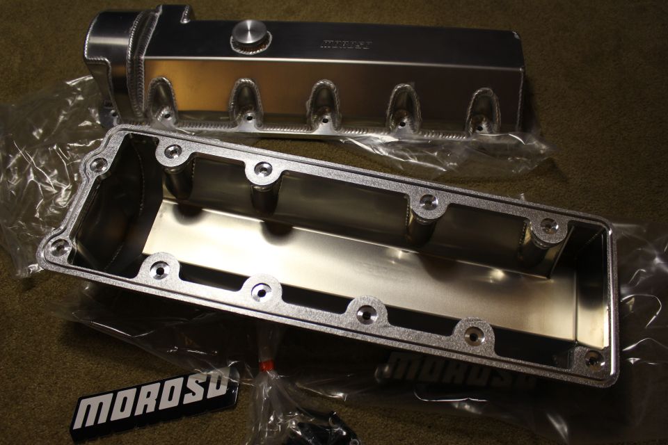 Aluminum valve cover beside its open underside showing baffle and bolt holes, MOROSO badges