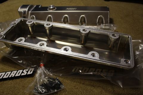 2003 Ford Crown Victoria - machined underside of a fabricated aluminum valve cover with bolt holes, shown with a hardware bag and MOROSO badges.