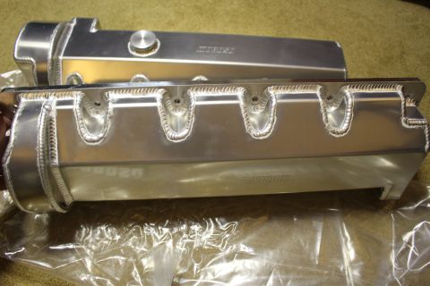 2003 Ford Crown Victoria - polished cast-aluminum valve cover and a hand-fabricated aluminum intake manifold with TIG-welded runner seams rest on a workbench.