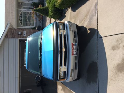 1995 Chevrolet Blazer - A blue and silver 1995 Chevrolet S-10 pickup truck is parked in a driveway in front of a house.