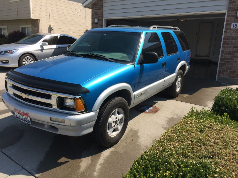Blue 1995 Chevrolet Blazer parked in driveway with a silver sedan behind it