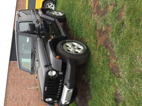 2013 Jeep Wrangler - A black 2013 Jeep Wrangler is parked on grass next to a yellow vehicle.
