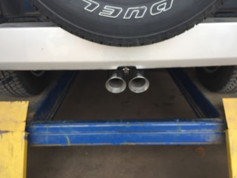 2013 Jeep Wrangler - The vehicle is elevated on a lift, revealing its dual exhaust system and spare tire.