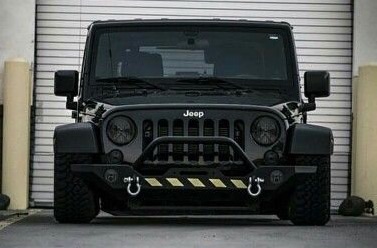 2013 Jeep Wrangler - A black Jeep Wrangler is parked in front of a garage door.