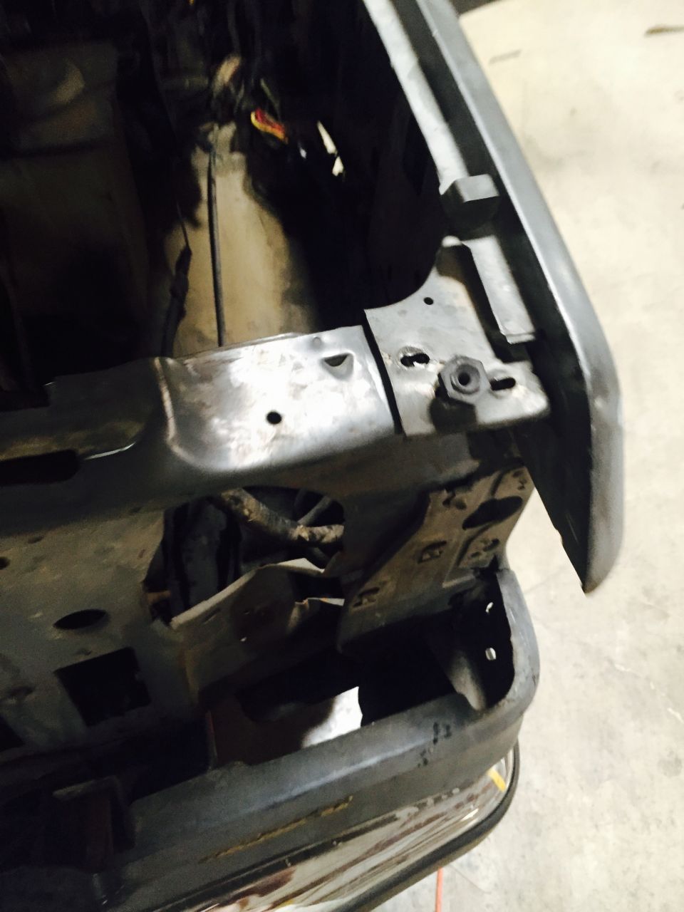 Close-up of a vehicle's front fender and frame, showing metalwork and some wiring