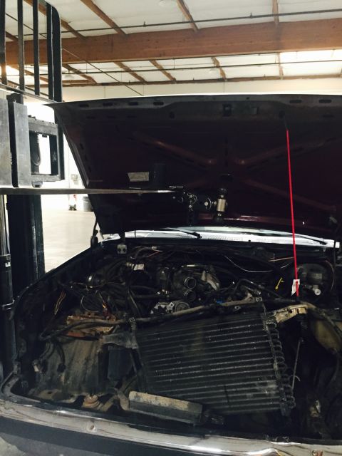 1988 Ford Bronco - The engine bay of a vehicle is exposed, revealing the radiator and various engine parts under the open hood.