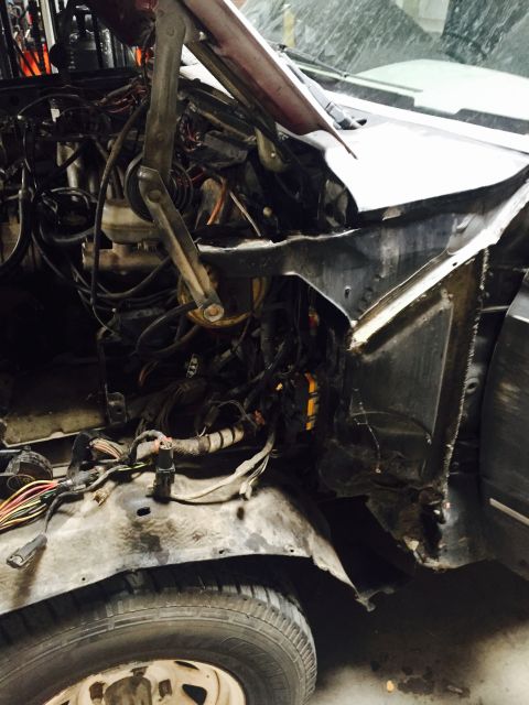 1988 Ford Bronco - The engine bay of a vehicle is shown with many wires and components exposed.