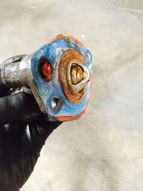 1988 Ford Bronco - A gloved hand holds a used thermostat housing, showing signs of rust and wear.