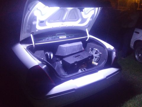 2000 Mercury Grand Marquis - The trunk of a car is open, illuminated by blue lights, revealing audio equipment and a toolbox.