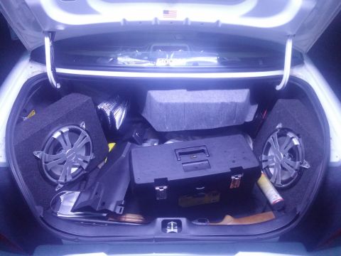 2000 Mercury Grand Marquis - The trunk of a car contains two subwoofers, a black toolbox, and other items, with a SuperMotors.net watermark visible.