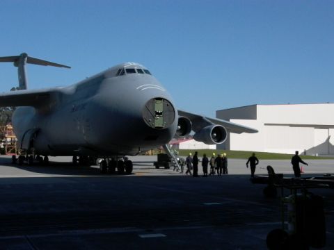 1990 Ford Bronco - A C-5 Galaxy military transport aircraft is parked on an airfield with a large hangar in the background.