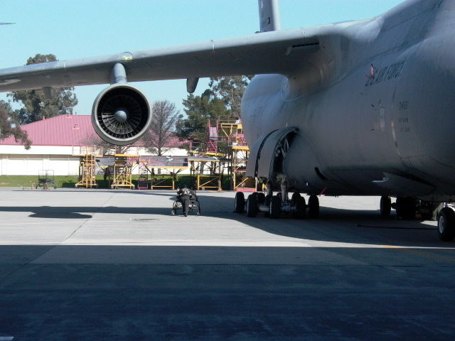 C-5 Galaxy aircraft wing and engine with a person in a wheelchair on tarmac