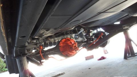 1972 Ford Ranchero - The underside of a vehicle is visible, supported by jack stands, with a bright orange differential housing.