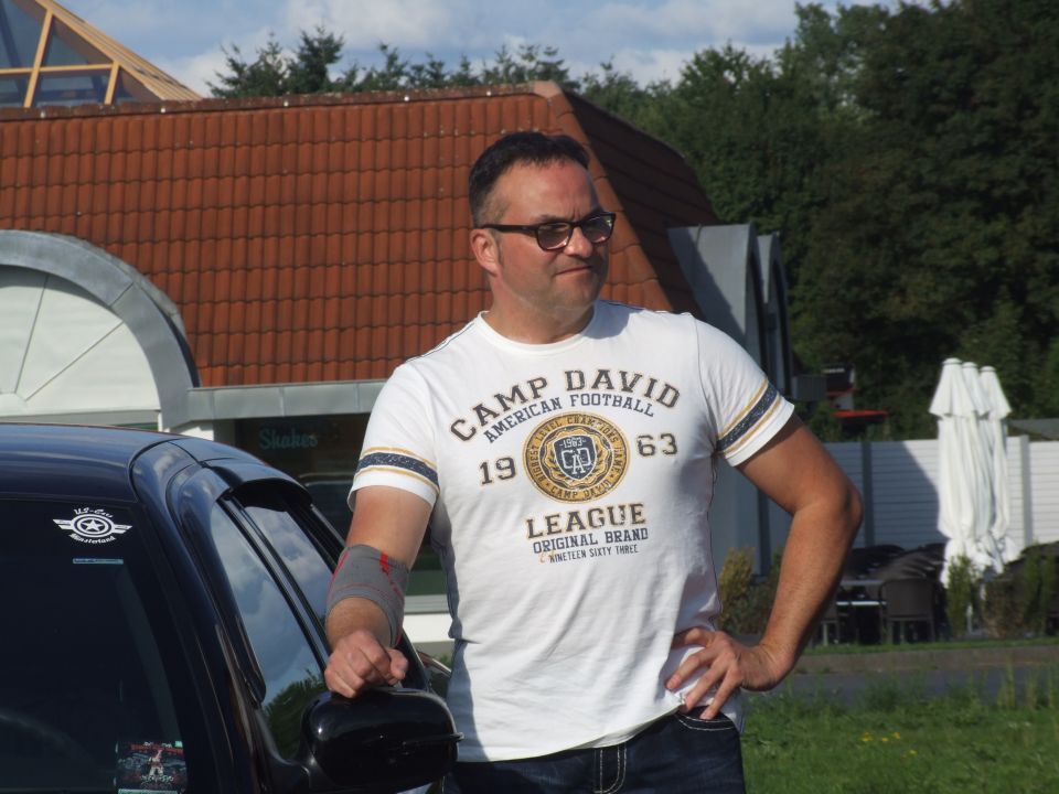 Black car side view with a man in a white t-shirt standing next to it