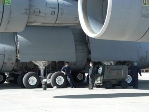1990 Ford Bronco - Ground crew members stand near the massive landing gear and engines of a large aircraft.