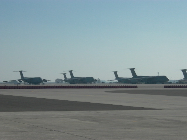 Several large cargo airplanes parked on an airfield under a clear blue sky