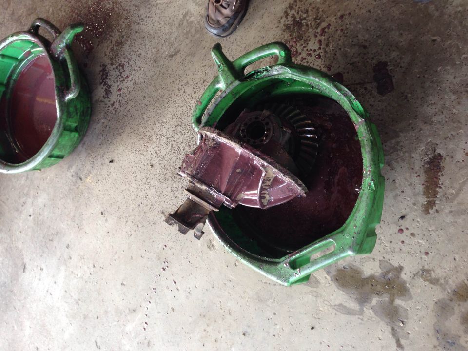 Green fluid drain pans with a broken differential housing and gears in one pan