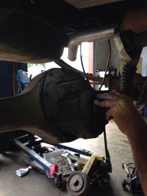 1979 Ford Bronco - Close-up view of a vehicle's rear differential and exhaust system, with a mechanic's hand visible.