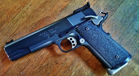 1996 Ford Bronco - A close-up view of a Colt 1911-A1 pistol chambered in 9mm, resting on a wooden table.